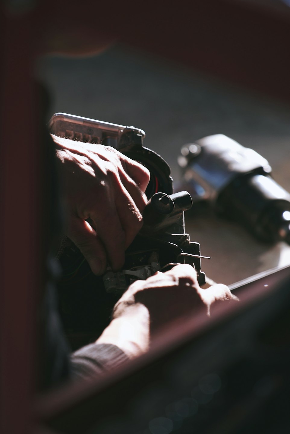 Technician's hands assembling intricate machinery with small tools.