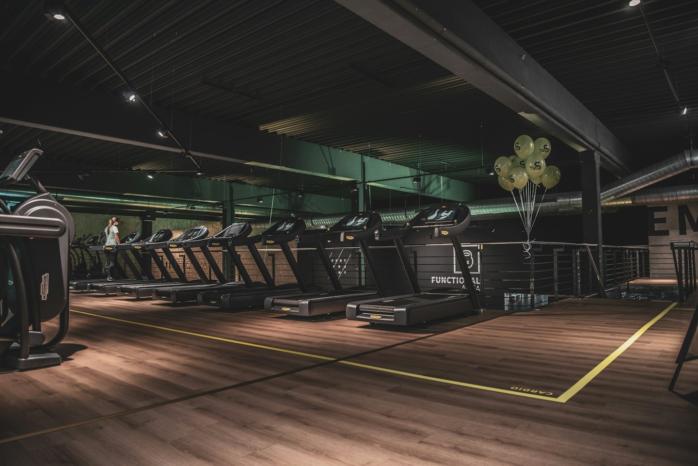 Woman walks on a treadmill in a gym's cardio zone.